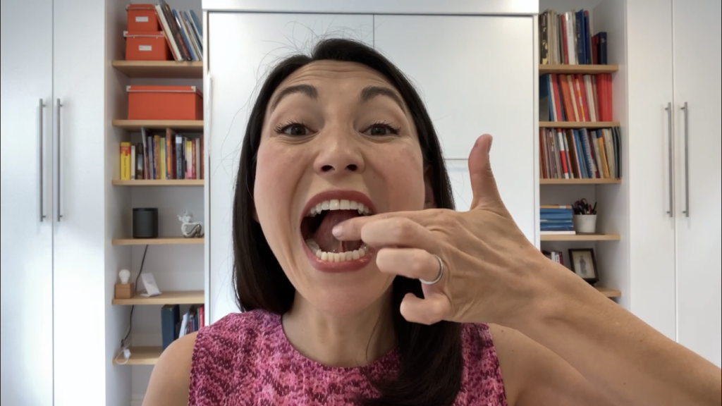 Close up of Laura with mouth open and tongue lifted, pointing to the frenulum underneath.